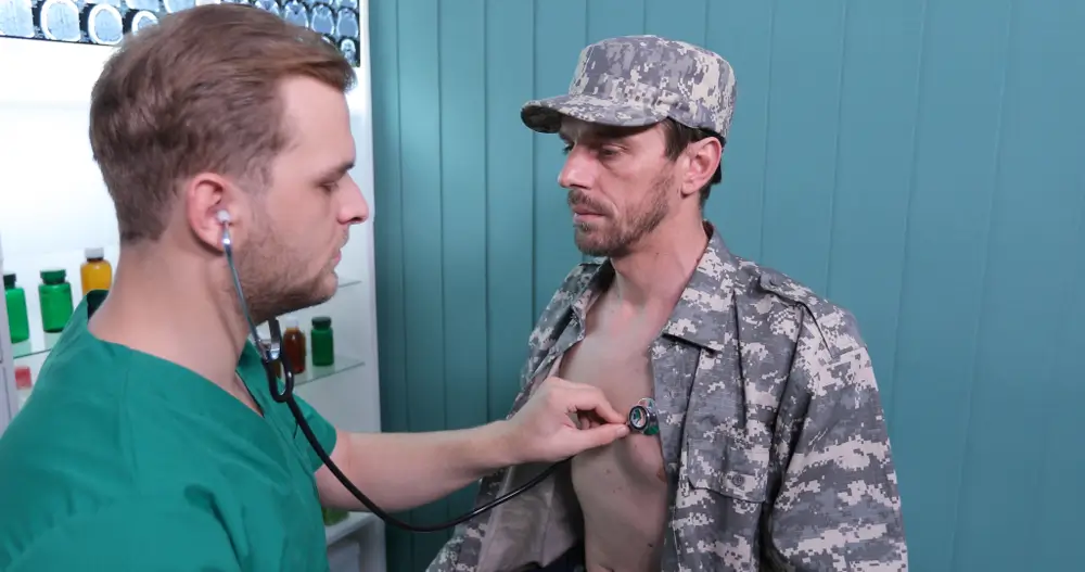 Medico militare esamina il torace di un soldato con lo stetoscopio durante una visita medica di accertamento.