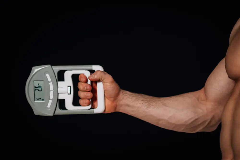 Braccio muscoloso che impugna un dinamometro digitale per un test di forza muscolare della mano.