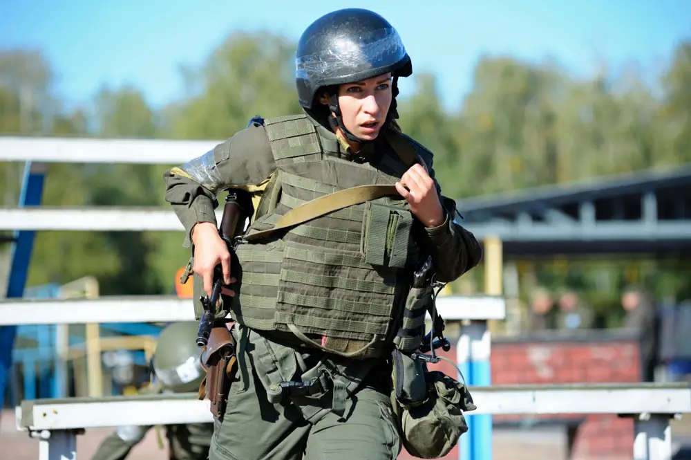 Una recluta corre con equipaggiamento completo durante le prove di efficienza fisica per il concorso militare.