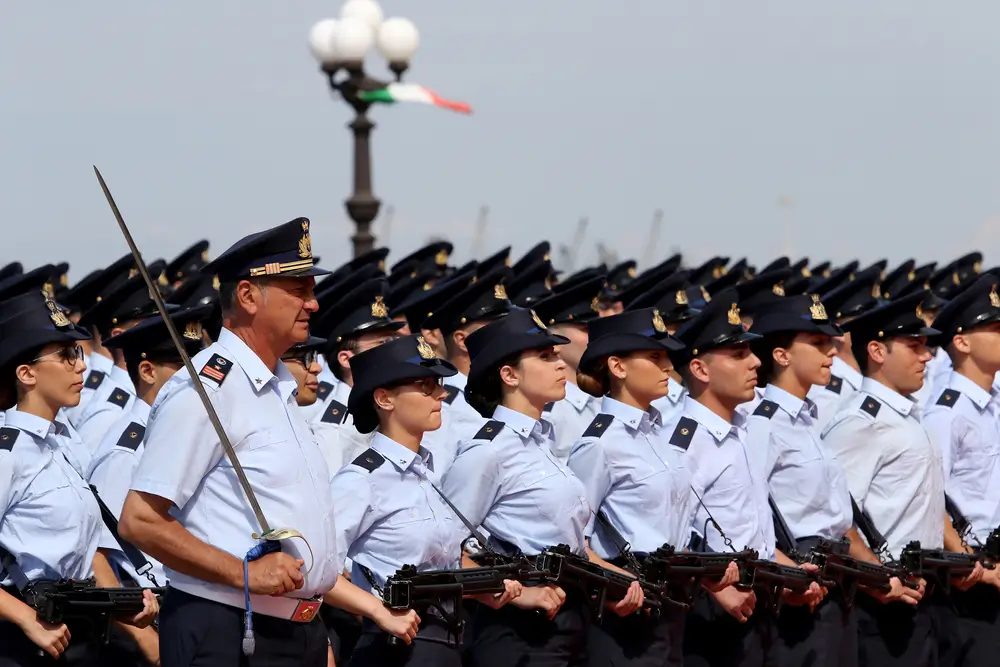 Cadetti dell'Accademia Militare di Modena schierati in uniforme durante una parata ufficiale con armi e sciabola.