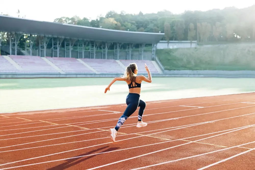 Giovane donna impegnata in una prova fisica di corsa su pista di atletica durante un test di idoneità.