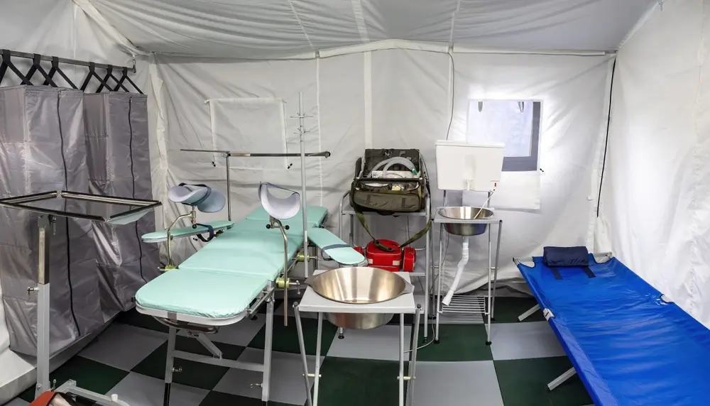 Attrezzature sanitarie in un ospedale da campo militare con lettino chirurgico e barella per l'assistenza medica.