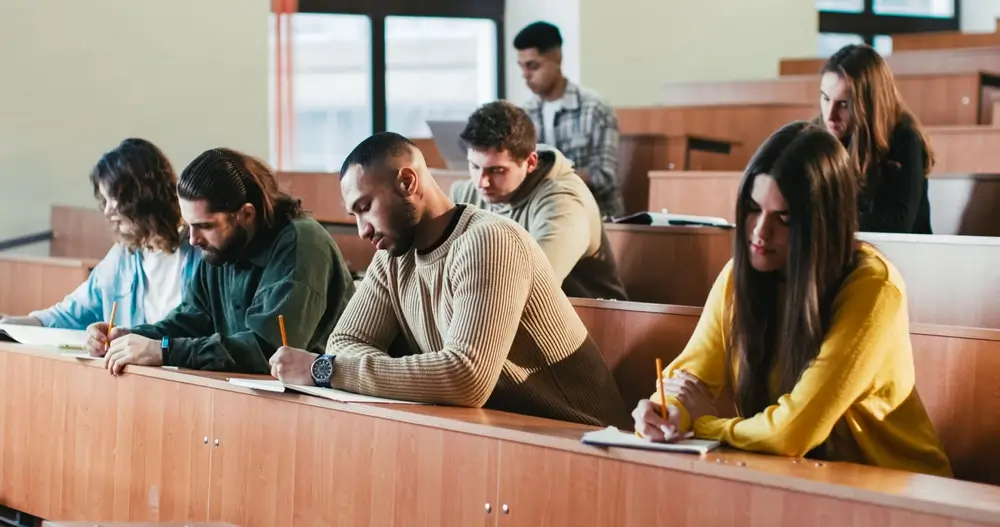 Allievi ufficiali seduti ai banchi di un'aula universitaria mentre prendono appunti durante una lezione.