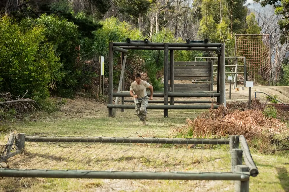Atleta che corre su un percorso a ostacoli all'aperto durante un allenamento fitness per le prove di efficienza fisica.