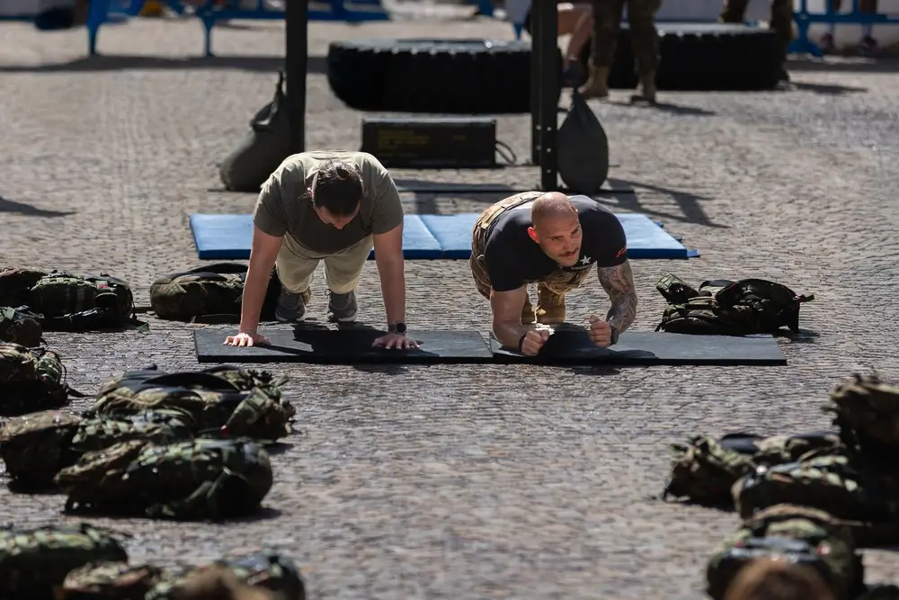 Allievi ufficiali impegnati in un'esercitazione fisica di plank durante l'addestramento militare all'aperto.