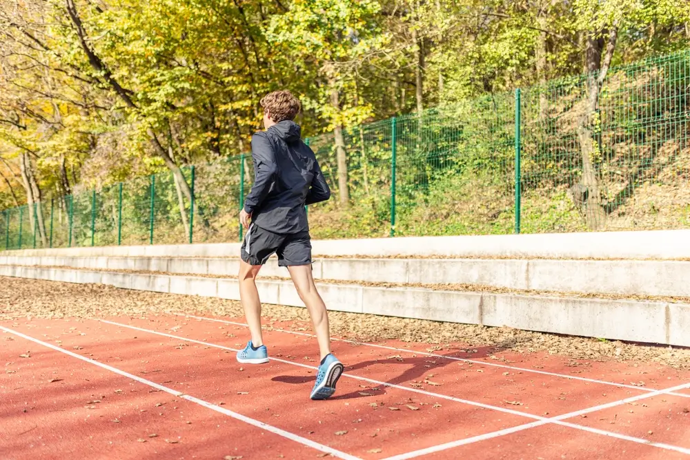 Candidato corre su pista di atletica durante una prova di efficienza fisica per l'addestramento militare.