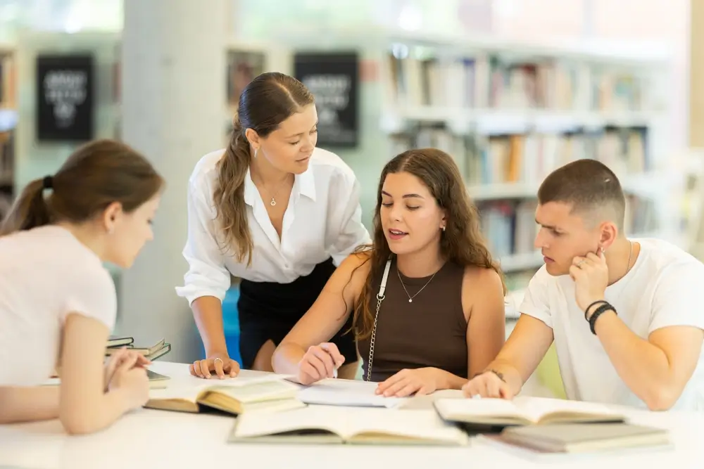 Allievi ufficiali e studenti che collaborano e studiano insieme su libri e appunti in una biblioteca accademica.