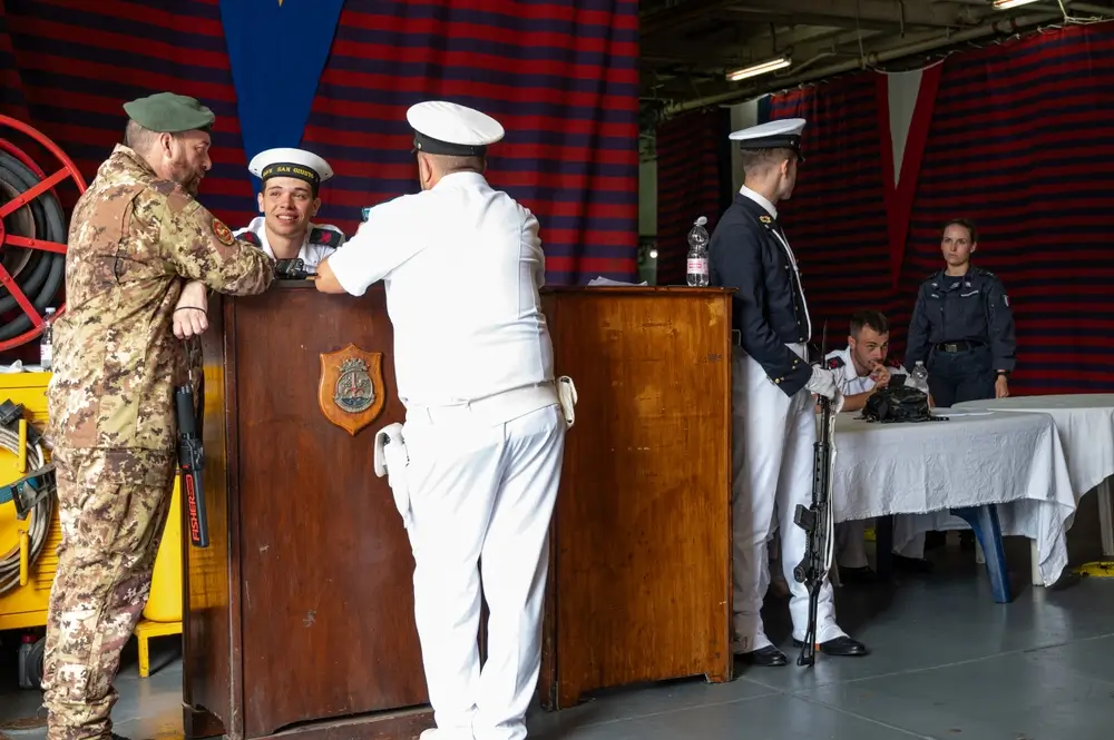 Ufficiale dell'Esercito Italiano in divisa mimetica e personale militare durante procedure di selezione in un ufficio.