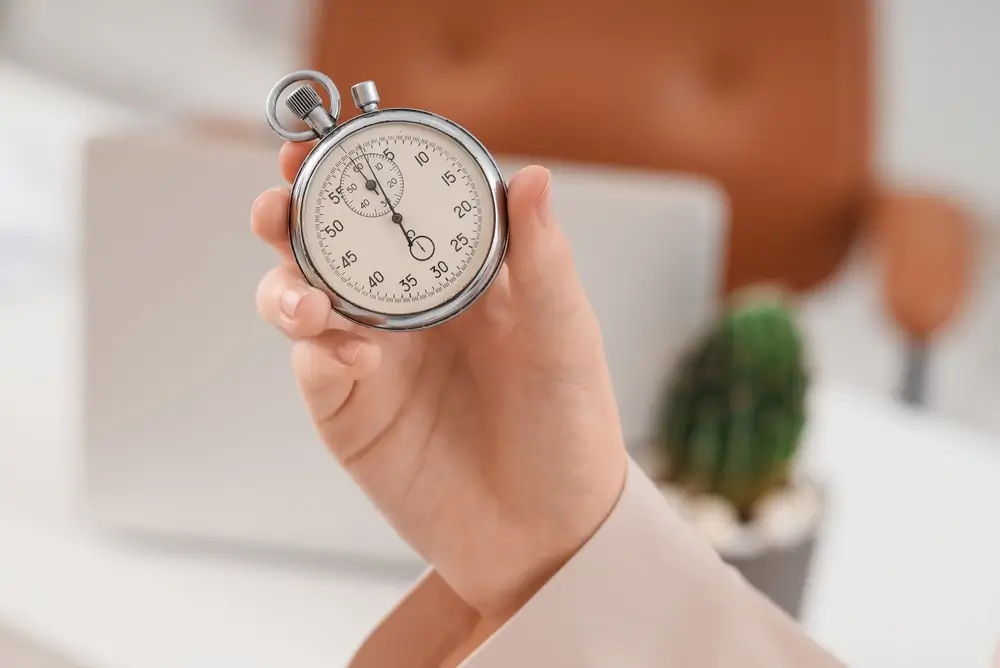 Cronometro analogico tenuto in mano per gestire il tempo e il countdown durante una prova d'esame.
