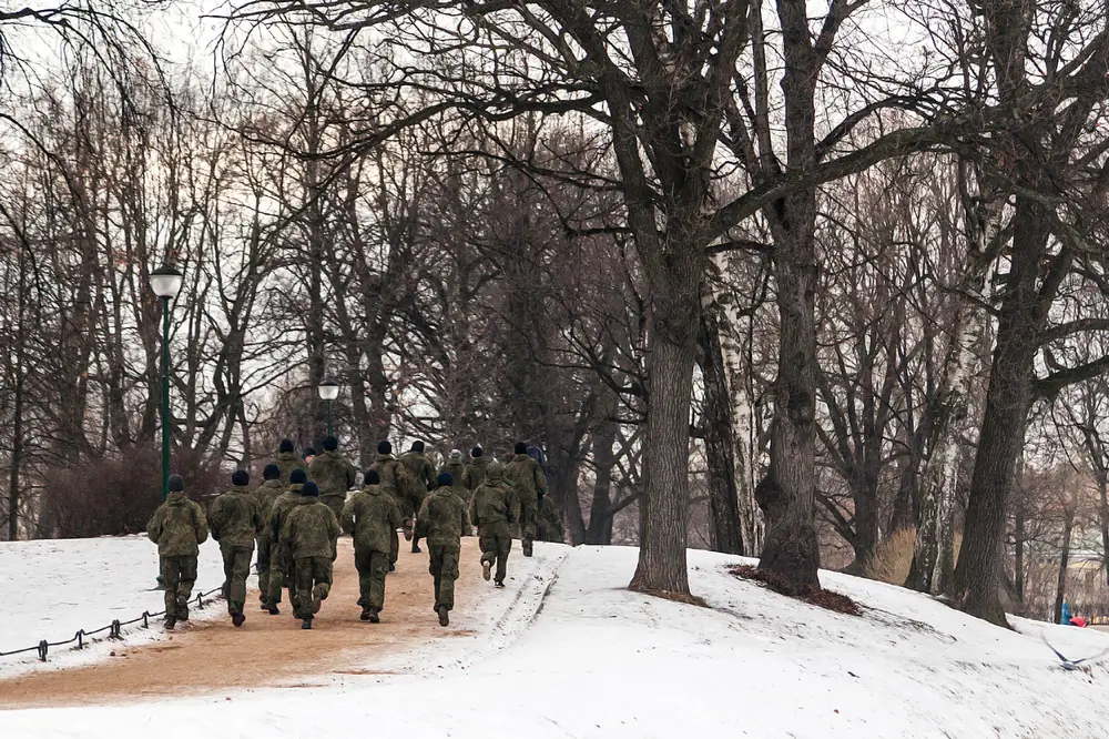 Gruppo di soldati in mimetica che corrono su un sentiero innevato durante un addestramento fisico cronometrato.