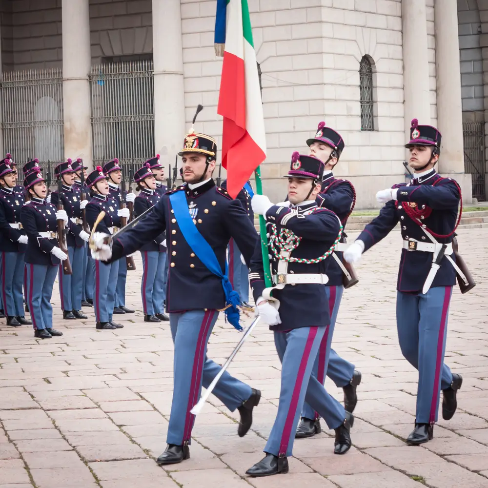 Cadetti dell'Accademia Militare di Modena in alta uniforme sfilano con la bandiera tricolore durante una cerimonia.